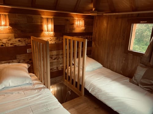 Houten slaapkamer met twee bedden, wiegjes, warm licht en tuinzicht in Domaine De Campagnac, Carsac-Aillac