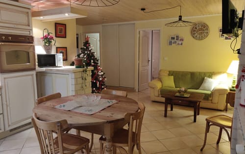 Séjour cosy de l'hôtel Location MarjoRI avec table à manger, canapé vert et décoration festive à Le Lauzet-Ubaye