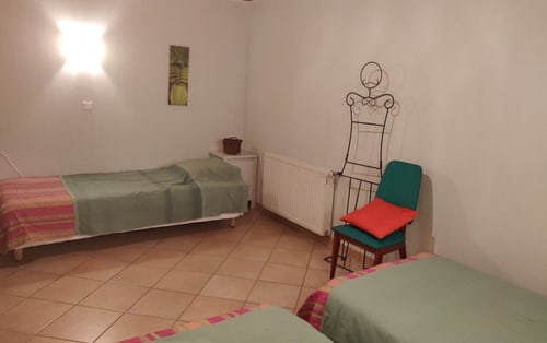 Chambre à coucher de l'hôtel MarjoRI au Lauzet-Ubaye avec lits, fauteuil et vue sur la montagne