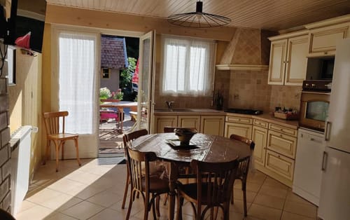 Cuisine-salle à manger spacieuse avec meubles en bois, table ronde, chaises et accès au jardin de l'appartement MarjoRI