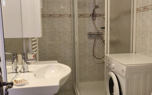 Salle de bain moderne avec lavabo, cabine de douche et machine à laver dans l'appartement Location MarjoRI, Le Lauzet-Ubaye