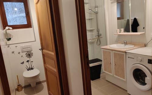 Salle de bains moderne avec toilettes, lavabo, lave-linge et douche à l'hôtel-appartement Marjori au Lauzet-Ubaye