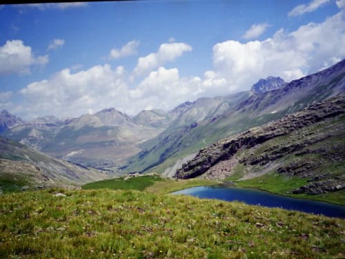 Prairie alpine avec lac bleu, montagnes et vallées verdoyantes près de Le Lauzet-Ubaye