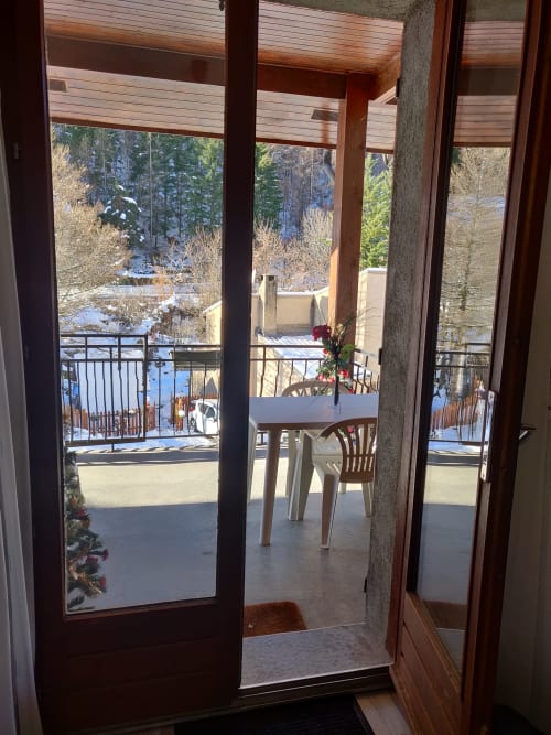 Balcon de l'appartement montagnard de l'hôtel Marjo RI au Lauzet-Ubaye avec table à manger et paysage forestier