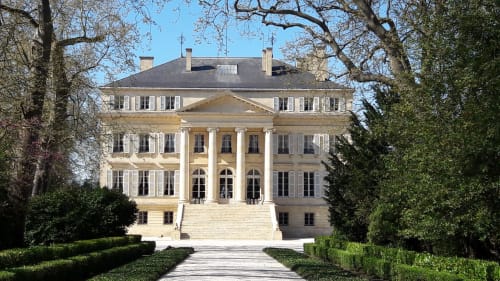 Entrada de la mansió neoclàssica Le Manoir Lacustre a Queyrac, França amb columnes i jardins curats
