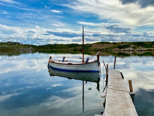 Amarrament tranquil a Le Manoir Lacustre, Queyrac, amb barca de pesca reflectida en aigües tranquil·les
