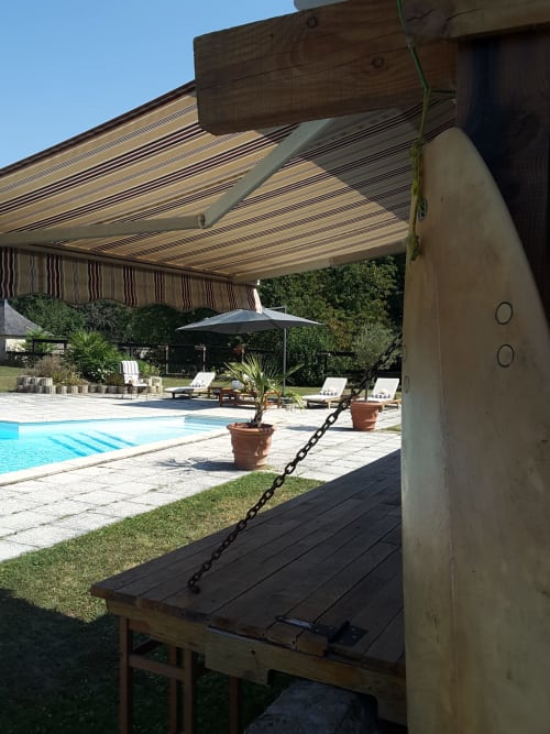 Striped awning framing pool and lounge area at Château de Ré boutique hotel in Le Petit Pressigny