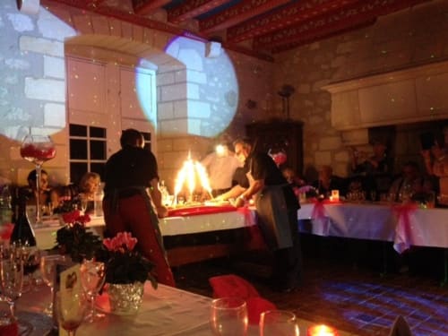Elegant evening event at Château de Ré with fireplace, projection, guests, and red-themed decor in Le Petit Pressigny