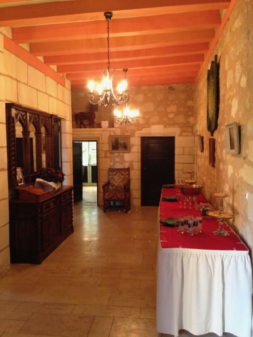 Elegant event space at Château de Ré with ornate chandelier, red-draped table, and rustic stone walls in Le Petit Pressigny.