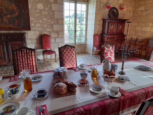 Élégante salle à manger du Château de Ré avec mise de table raffinée, mobilier d'époque et murs en pierre au Petit Pressigny