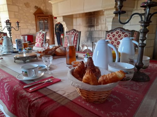 Table de petit-déjeuner élégante au Château de Ré avec croissants, service à café et linges rouges à motifs au Petit Pressigny