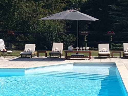 Château de Ré pool area in Le Petit Pressigny with lounge chairs, umbrella, and manicured hedges
