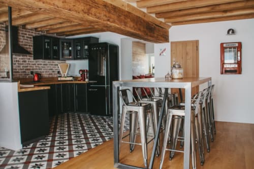 Cuisine moderne avec armoires noires, poutres apparentes et bar style industriel aux Chambres d'hôtes Saint Jean