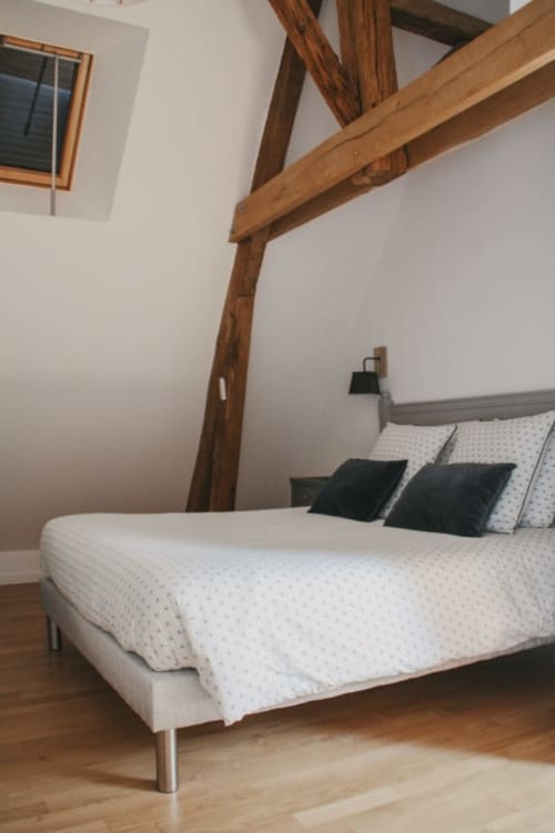 Chambre aux poutres apparentes aux Chambres d'hôtes Saint Jean à Nogent le Rotrou, avec un lit aux draps blancs