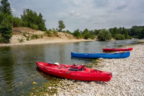 Kayaks rouges et bleus sur la plage fluviale près de Nogent-le-Rotrou avec collines vertes et arbres