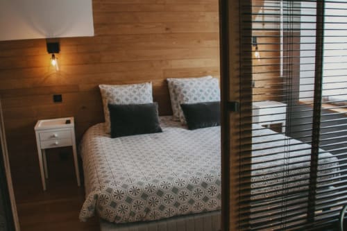 Chambre accueillante aux murs en bois chaud, literie patterned et vue sur la ville à travers les volets