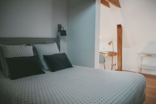 Chambre accueillante aux Chambres d'hôtes Saint Jean à Nogent le Rotrou : murs bleus, bureau en bois et literie à motifs