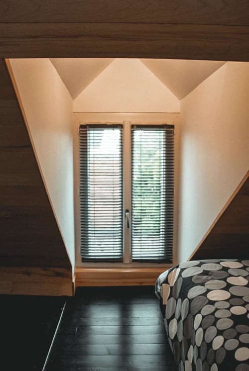 Chambre moderne aux Chambres d'hôtes Saint Jean avec plafond géométrique, fenêtres doubles avec volets, parquet foncé
