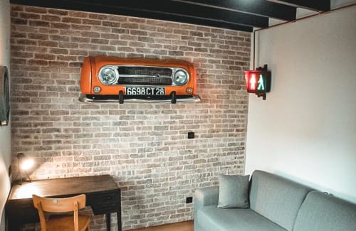 Chambre moderne aux Chambres d'hôtes Saint Jean avec mur de brique, art automobile vintage orange, bureau, canapé et panneau exit vert