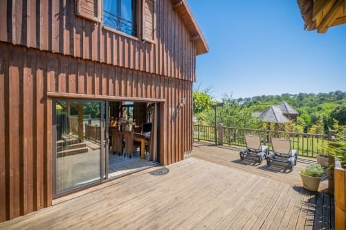 Houten terras aan Domaine De Campagnac met ligbedden, landelijk uitzicht en moderne schuurarchitectuur