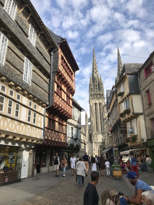 Rue pavée historique de Quimper avec maisons à colombages et flèche de cathédrale gothique, près des Gîtes De L'odet