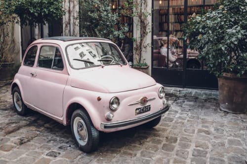 Pink vintage Fiat 500 parked at Habitation I'SEO hotel courtyard in Sainte-Anne, Guadeloupe