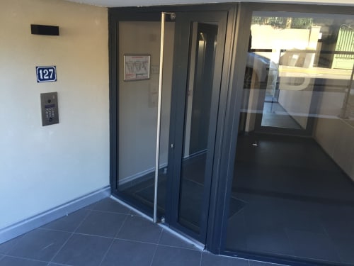 Entrée de l'appartement Ô de Mer B à La Cadière d'Azur avec porte noire moderne et interphone, unité 127