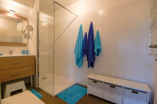 Salle de bain moderne avec douche italienne, vasque en bois et serviettes turquoise dans un luxueux appartement provençal