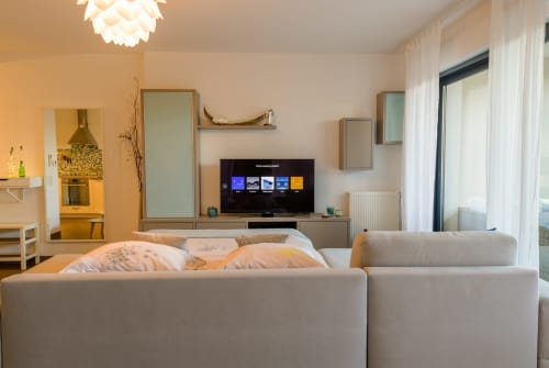 Séjour moderne à La Cadière d'Azur avec canapé beige, téléviseur écran plat, placards miroirs et terrasse jardin