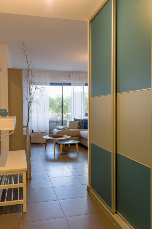 Entrée d'appartement provençal avec portes modernes vert canard et sauge s'ouvrant sur un lumineux séjour avec vue sur le jardin