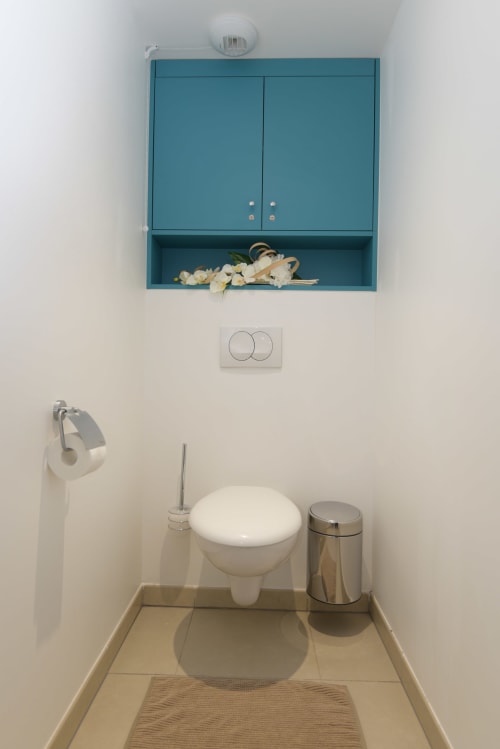 Salle de bain avec meuble teal, toilettes blanches et poubelle en acier inoxydable dans l'appartement Ô de Mer C, Provence