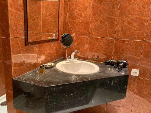 Lavabo moderne avec plan de travail en marbre noir et murs en carrelage orange au Château de Ré, Le Petit Pressigny
