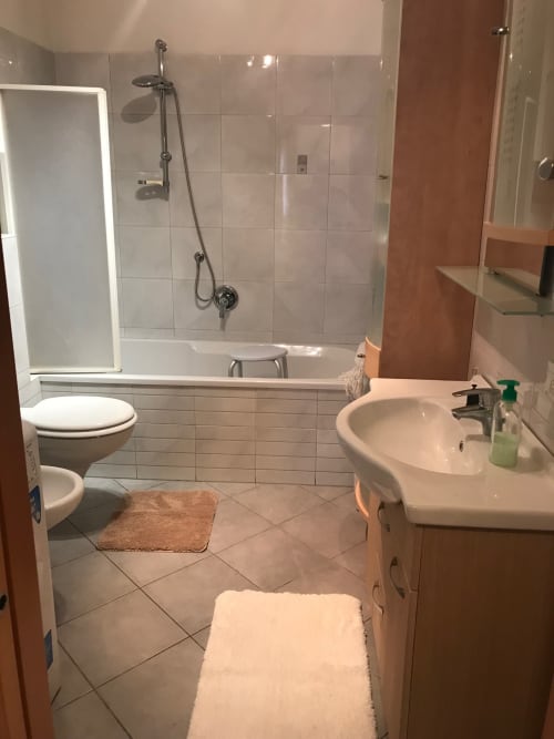 Modern bathroom in Giustina Apartment with white tile, sink, toilet, bathtub with shower, and heated towel racks