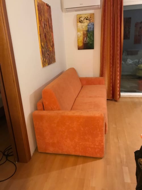 Orange armchair in modern sitting area at Giustina Apartment in Gargazzone with artwork and mountain views