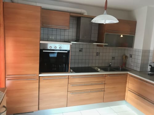 Modern kitchen with wooden cabinets, stainless steel oven, and white tile backsplash in Giustina Apartment, Gargazzone
