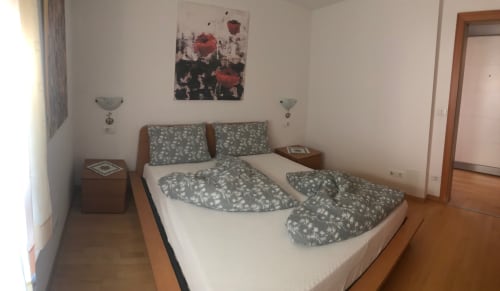 Bright bedroom at Appartamento Giustina in Gargazzone with queen bed, patterned bedding, wooden nightstands, and mountain