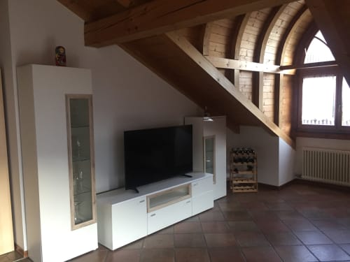 Apartment Giustina attic with TV, white furniture, arched windows with mountain views, and wooden beams