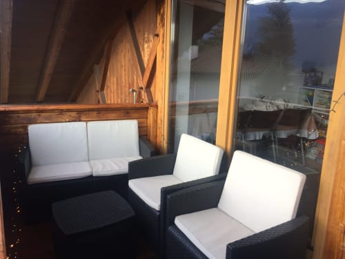 Outdoor seating area at Appartamento Giustina with black wicker chairs, white cushions, and mountain views in Gargazzone