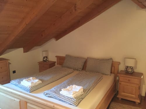 Cozy attic bedroom at Appartamento Giustina with twin beds, wooden beams, checkered bedding, and mountain views in Gargazzone