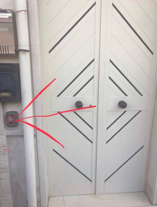 White double doors with diagonal pattern at Appartamento Giustina in Gargazzone, with red arrows pointing to door handles