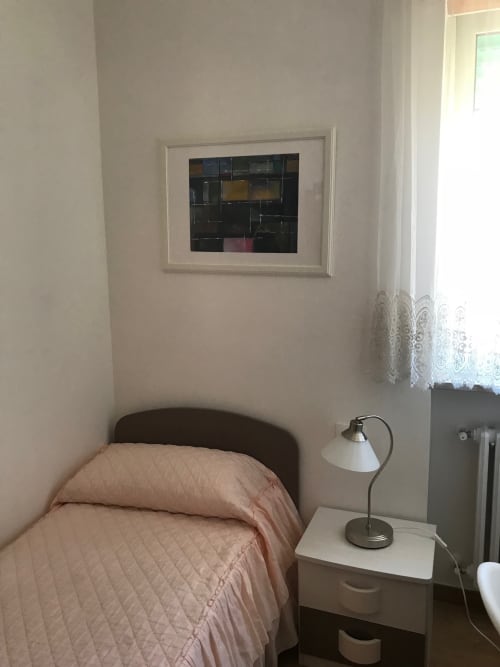Cozy bedroom in Appartamento Giustina, Gargazzone with pink bedding, bedside lamp, and framed artwork on wall