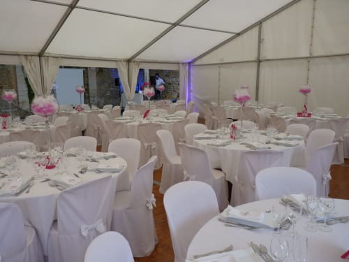 Elegant white-decorated wedding reception tent at Château de Ré with pink floral centerpieces and formal table settings in Le