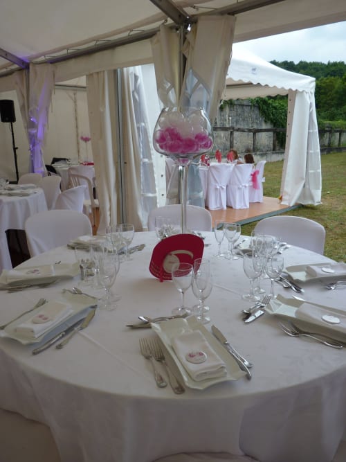 Elegant outdoor wedding reception tent at Château de Ré with white linens, pink floral centerpieces, and formal place
