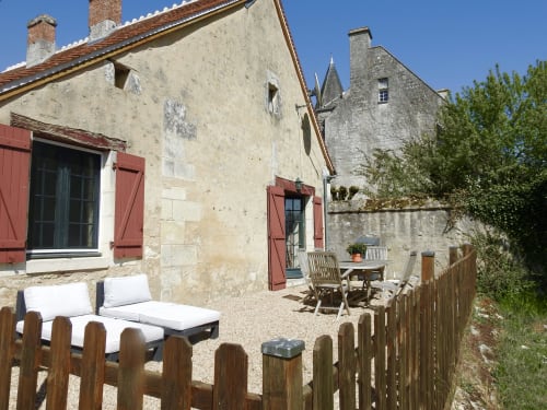 Château de Ré guesthouse courtyard with terrace seating, stone buildings and red shutters in Le Petit Pressigny