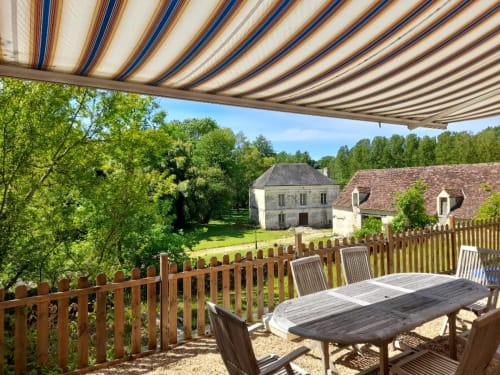 Retractable awning terrace at Château de Ré with wooden dining table overlooking French countryside estate