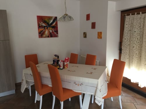 Dining area with orange chairs and white tablecloth at Appartamento Giustina in Gargazzone