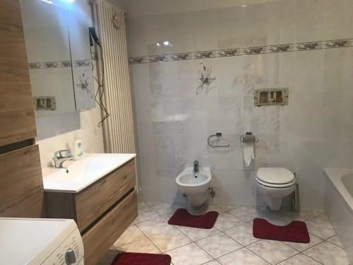 Modern bathroom in Gargazzone apartment with double sinks, bidet, toilet, and heated towel rack
