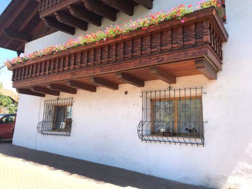 Traditional Alpine building with ornate wooden balcony and vibrant flowers in Gargazzone