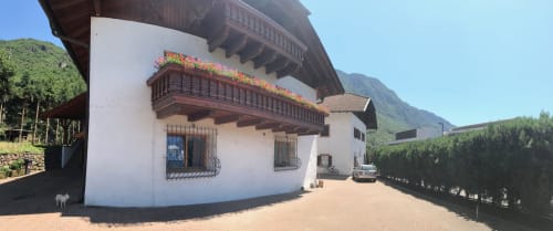 Appartamento Giustina exterior in Gargazzone, alpine resort with white walls, wooden balcony with flowers, and mountain views