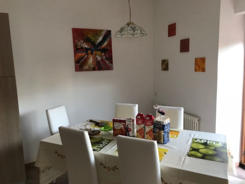 Bright dining area in 2-bedroom apartment with white chairs, table set with juice cartons, and colorful artwork on walls